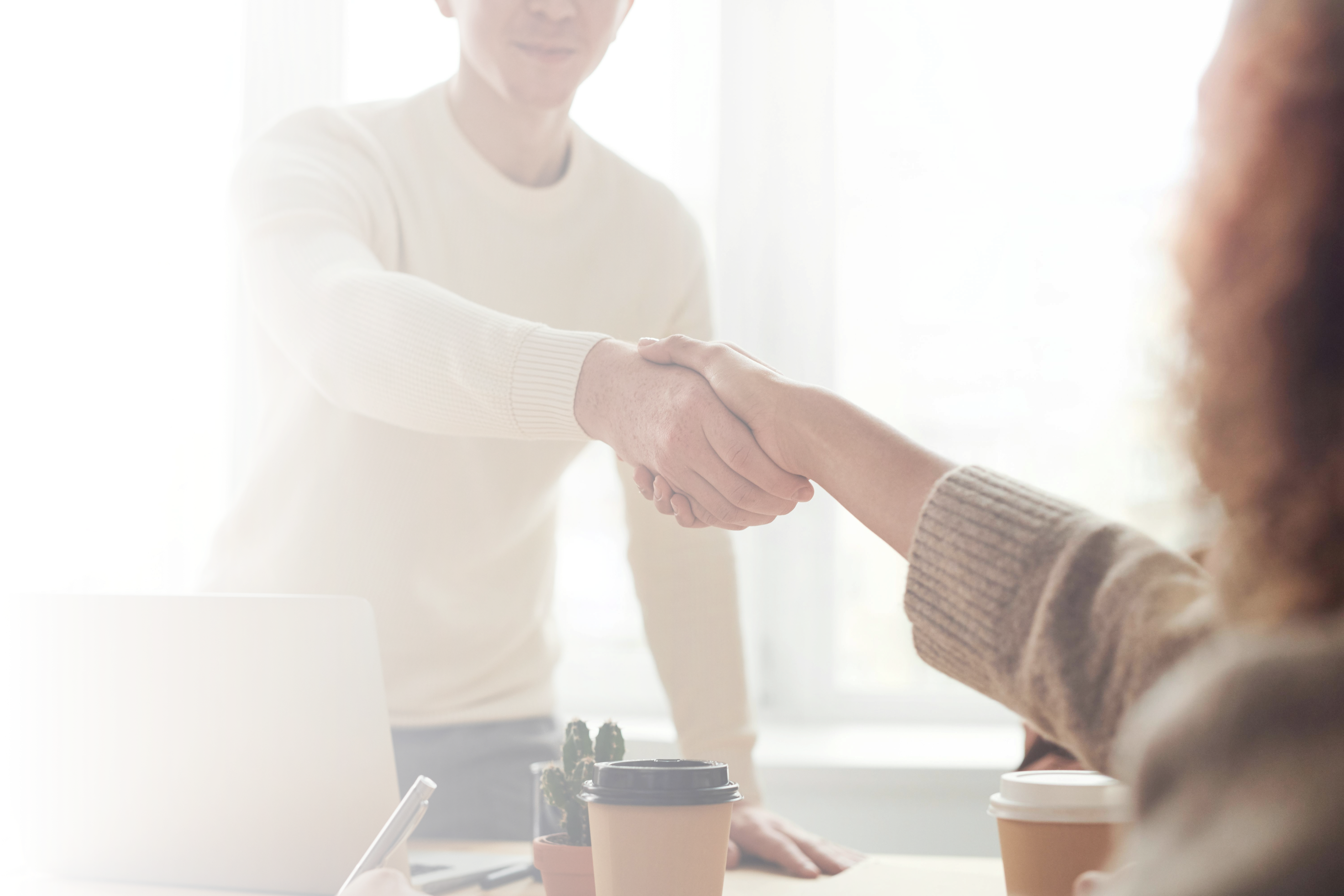 man and woman at a office
      table shaking hands